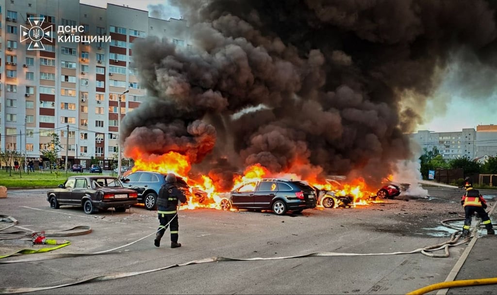 En esta imagen, proporcionada por el Servicio Ucraniano de Emergencias, bomberos intentan sofocar las llamas en unos autos tras un ataque con drones rusos en la región de Kiev, Ucrania.