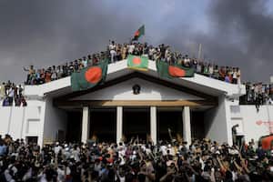 Manifestantes antigubernamentales exhiben la bandera nacional de Bangladesh mientras asaltan el palacio de la primera ministra, Sheikh Hasina, en Dhaka, el 5 de agosto de 2024 (Foto de K M ASAD / AFP)