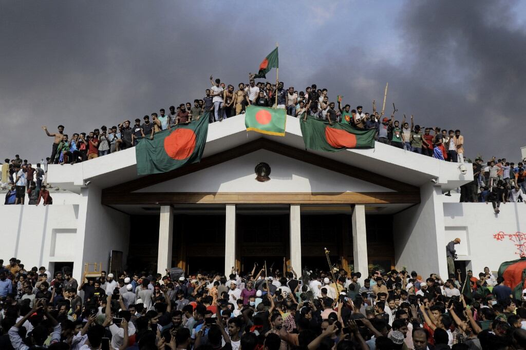 Manifestantes antigubernamentales exhiben la bandera nacional de Bangladesh mientras asaltan el palacio de la primera ministra, Sheikh Hasina, en Dhaka, el 5 de agosto de 2024 (Foto de K M ASAD / AFP)