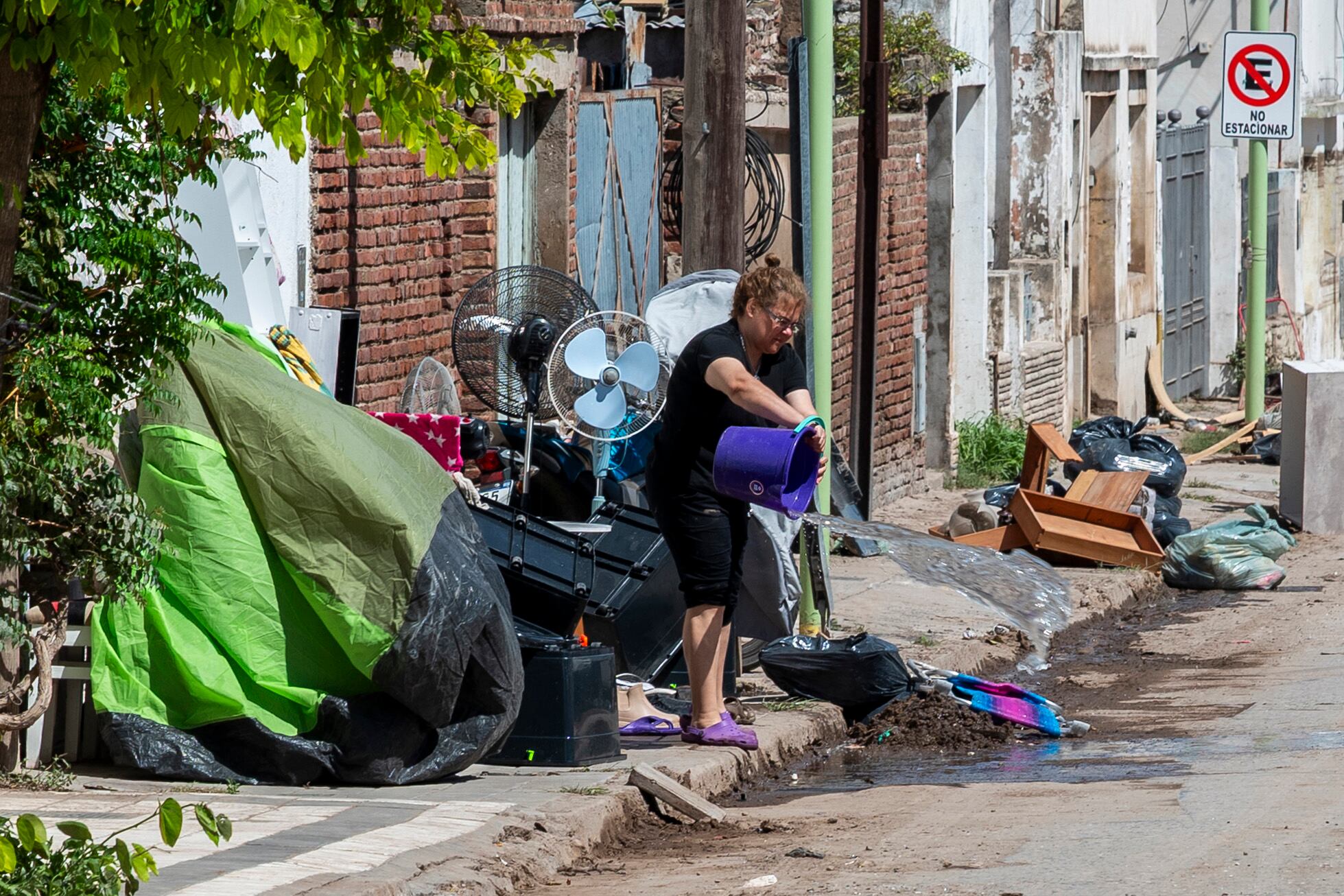 Una mujer arroja un balde de agua en una calle durante la limpieza en Bahía Blanca, a 600 km al sur de Buenos Aires, el 10 de marzo de 2025. Las fuertes lluvias dejaron al menos dieciséis muertos, provocaron evacuaciones masivas, inundaron hospitales y derrumbaron tramos de asfalto. Los rescatistas continúan el lunes buscando sobrevivientes de la tormenta sin precedentes que inundó la ciudad argentina de Bahía Blanca, azotada por fuertes lluvias que dejaron 16 muertos, cientos de desaparecidos y millones de dólares en pérdidas. (Foto de PABLO PRESTI / AFP)