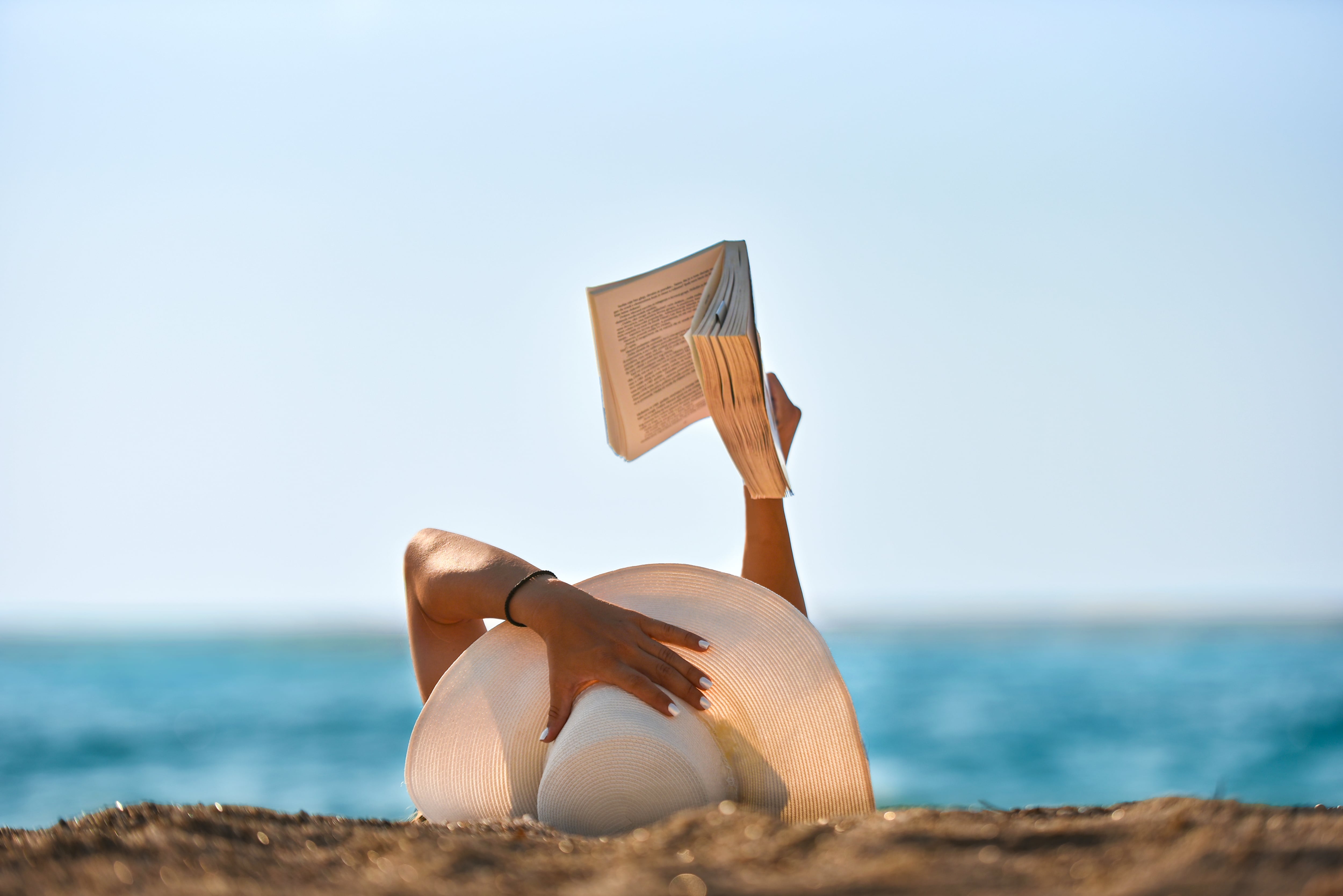 Foto de archivo de una joven leyendo un libro en la playa