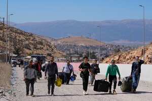 La gente carga su equipaje mientras cruza a pie a Siria, a través de un cráter causado por los ataques aéreos israelíes que tenían como objetivo bloquear la carretera Beirut-Damasco en el cruce de Masnaa, en el valle oriental de Bekaa, Líbano, el sábado 5 de octubre de 2024. (Foto AP /Hassan Ammar)