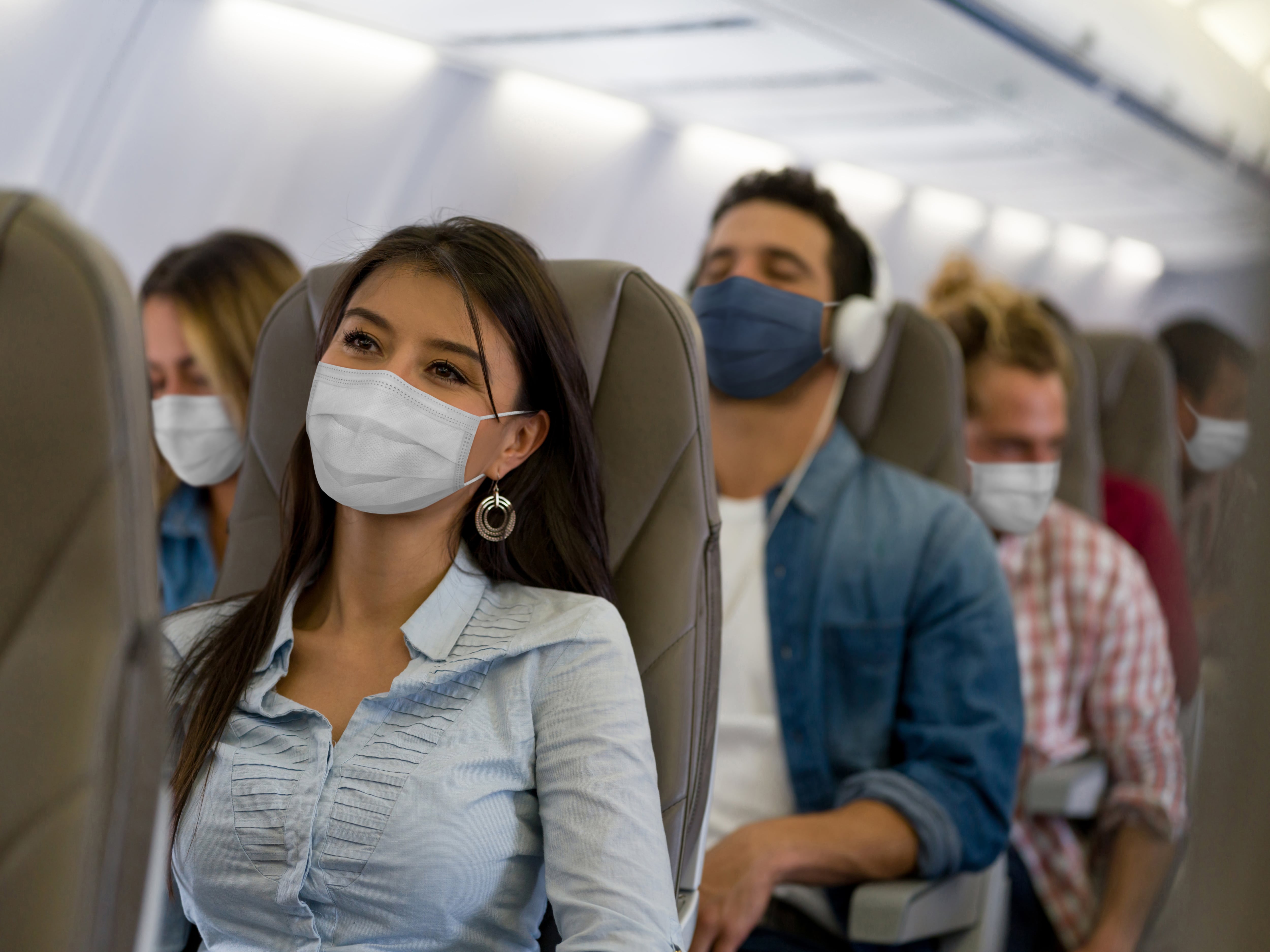 Retrato de una mujer latinoamericana que viaja en avión con mascarilla durante la pandemia de COVID-19.