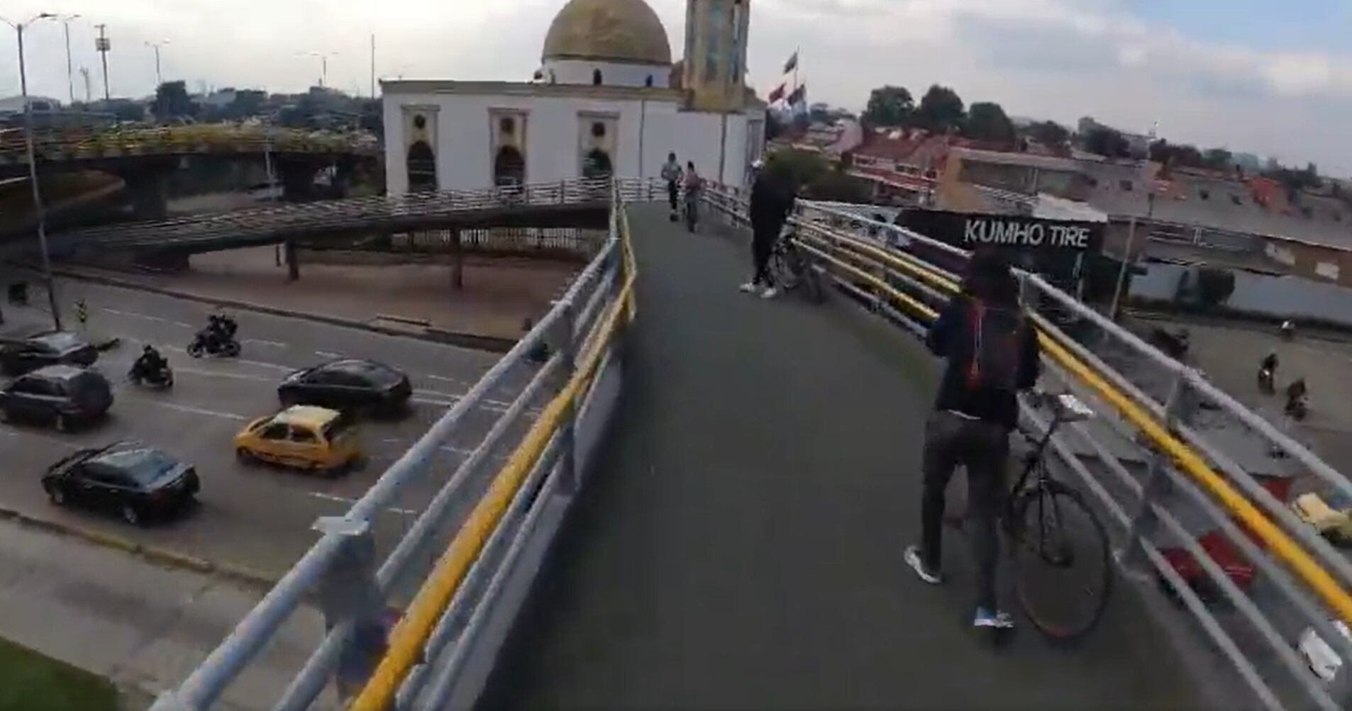 . El joven muestra, con una cámara que llevaba en su casco, el momento en que inicia su trayecto por el puente y a medida que lo recorre, y se aproxima casi al final del mismo, dos hombres van en bicicleta y fingen estar parados por un momento, para luego proceder con el atraco