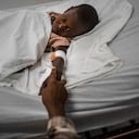 Rickson Beaubrun, quien resultó herido por una bala perdida mientras dormía en su cama en Cite Soleil, sostiene la mano de su hermana mientras se recupera en una clínica administrada por Médicos Sin Fronteras en el barrio Tabarre de Port-au-Prince, Haití, el jueves 11 de noviembre. 3 de enero de 2022.