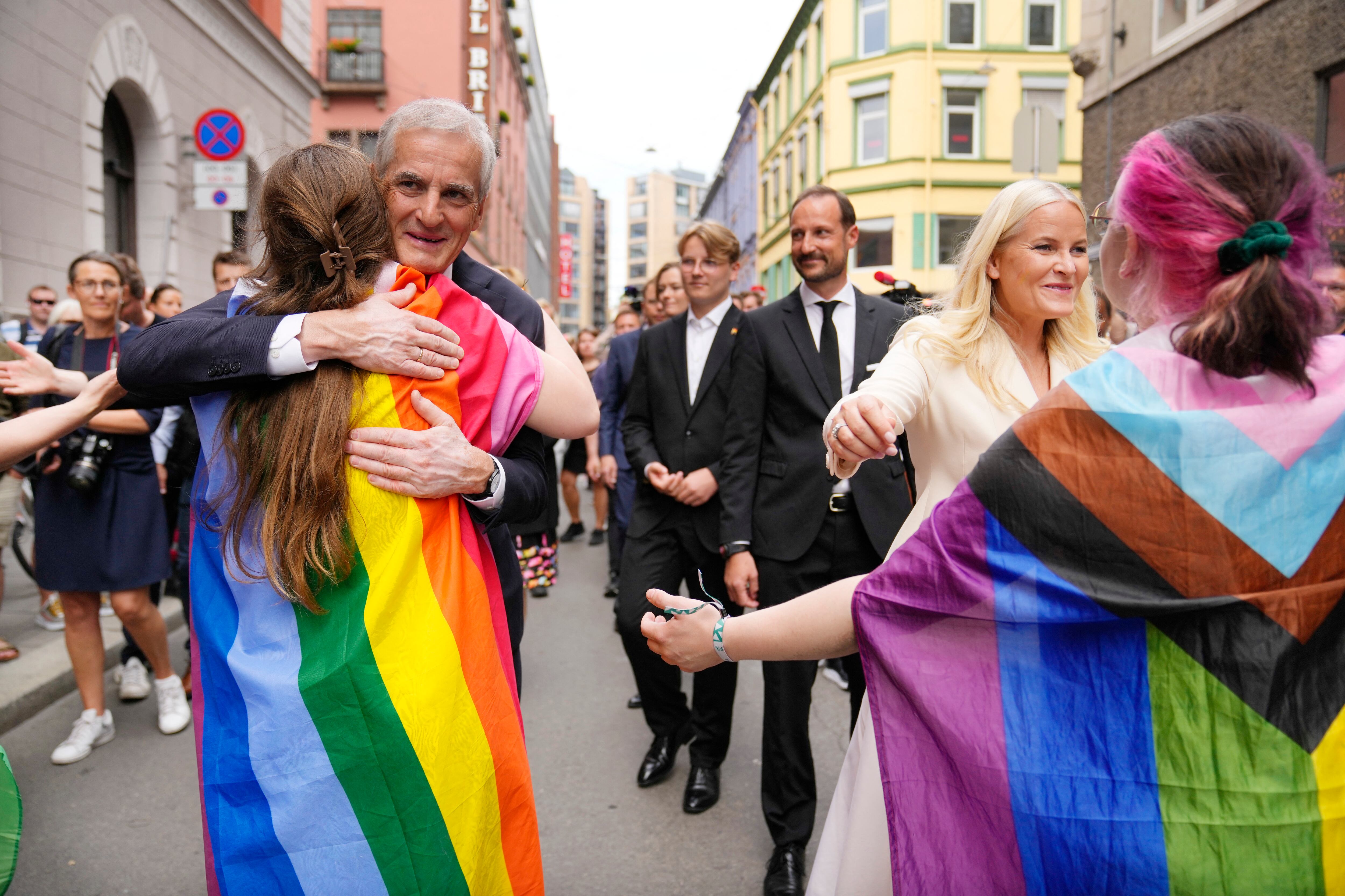 El primer ministro noruego Jonas Gahr Store y la princesa heredera Mette-Marit de Noruega abrazan a las personas con un arcoíris y una bandera de progreso mientras visitan la escena del crimen el 25 de junio de 2022, luego de un tiroteo afuera de pubs y clubes nocturnos en el centro de Oslo que mató a dos personas. hiriendo 21. (Foto de Javad Parsa / NTB / AFP) / Noruega FUERA