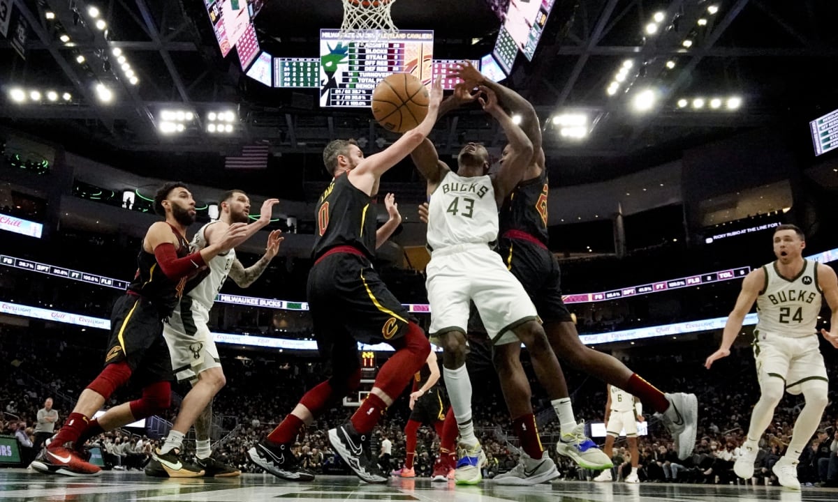 Milwaukee Bucks' Thanasis Antetokounmpo is fouled as he shoots between Cleveland Cavaliers' Kevin Love and Ed Davis during the second half of an NBA basketball game Saturday, Dec. 18, 2021, in Milwaukee. (AP/Morry Gash)