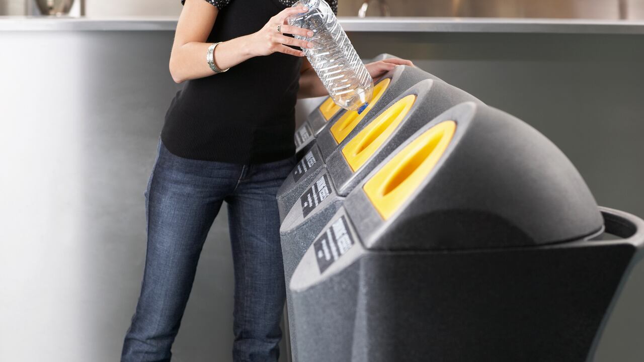 Mujer reciclando una botella de plástico. Reciclaje de plástico