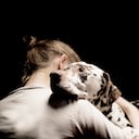 Joven abrazando a su perro; foto de estudio