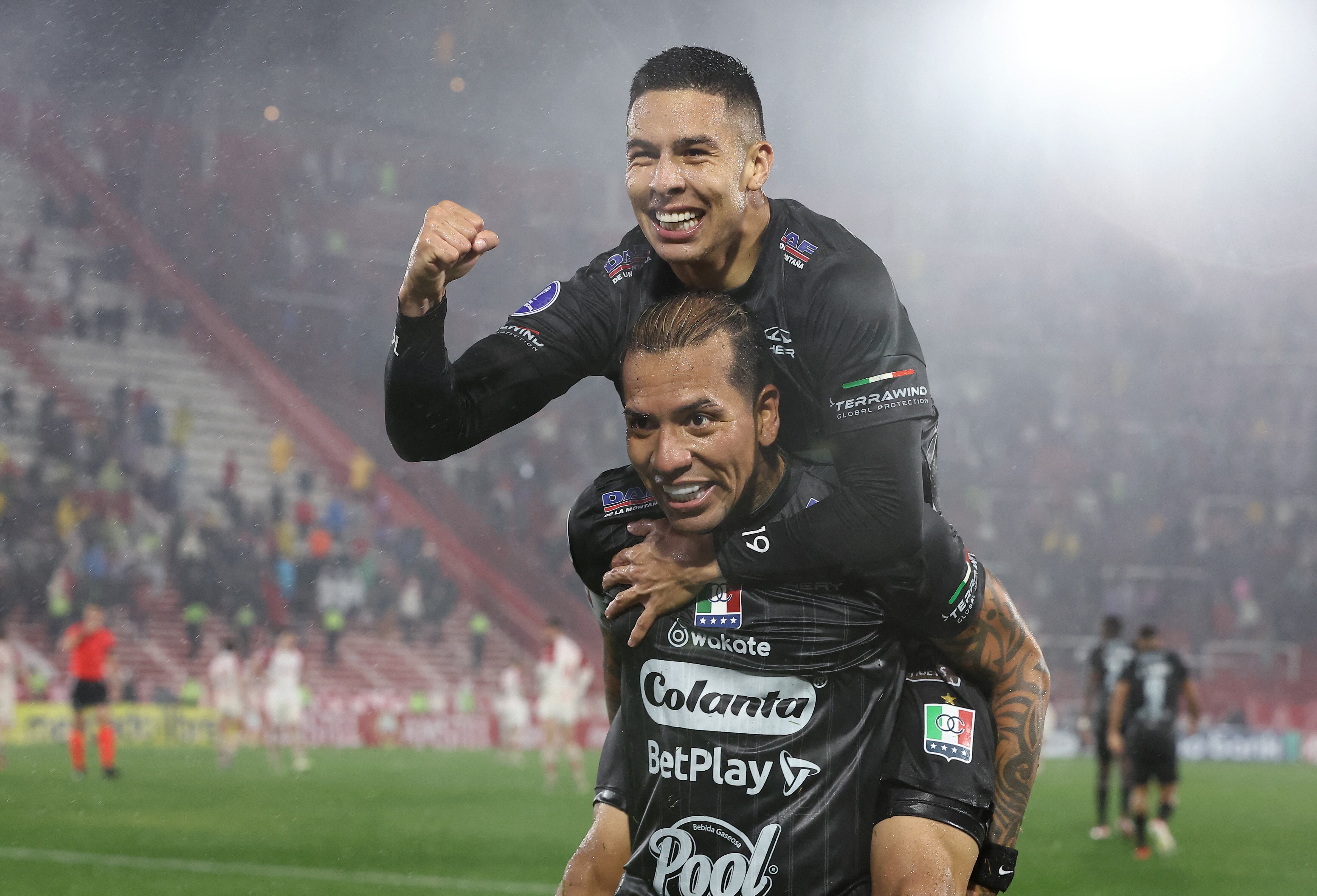 Once Caldas' forward #17 Dayro Moreno (bottom) celebrates after scoring his second goal with teammate midfielder #19 Mateo Garcia during the Copa Sudamericana round of 16 second leg football match between Argentina's Huracan and Colombia's Once Caldas at the Tomas Adolfo Duco Stadium in Buenos Aires on August 19, 2025. (Photo by ALEJANDRO PAGNI / AFP)