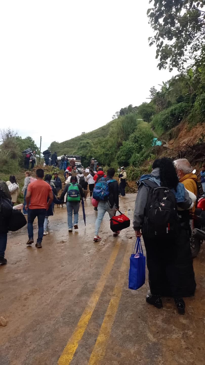 Las personas deben cruzar el derrumbe a pie para llegar a sus destinos.