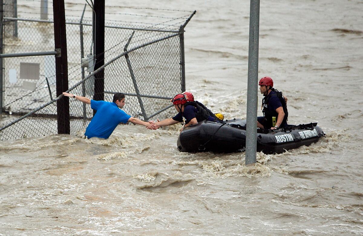 El personal de rescate agarra la mano de un hombre atrapado entre la corriente de agua en Austin, Texas. (AP)