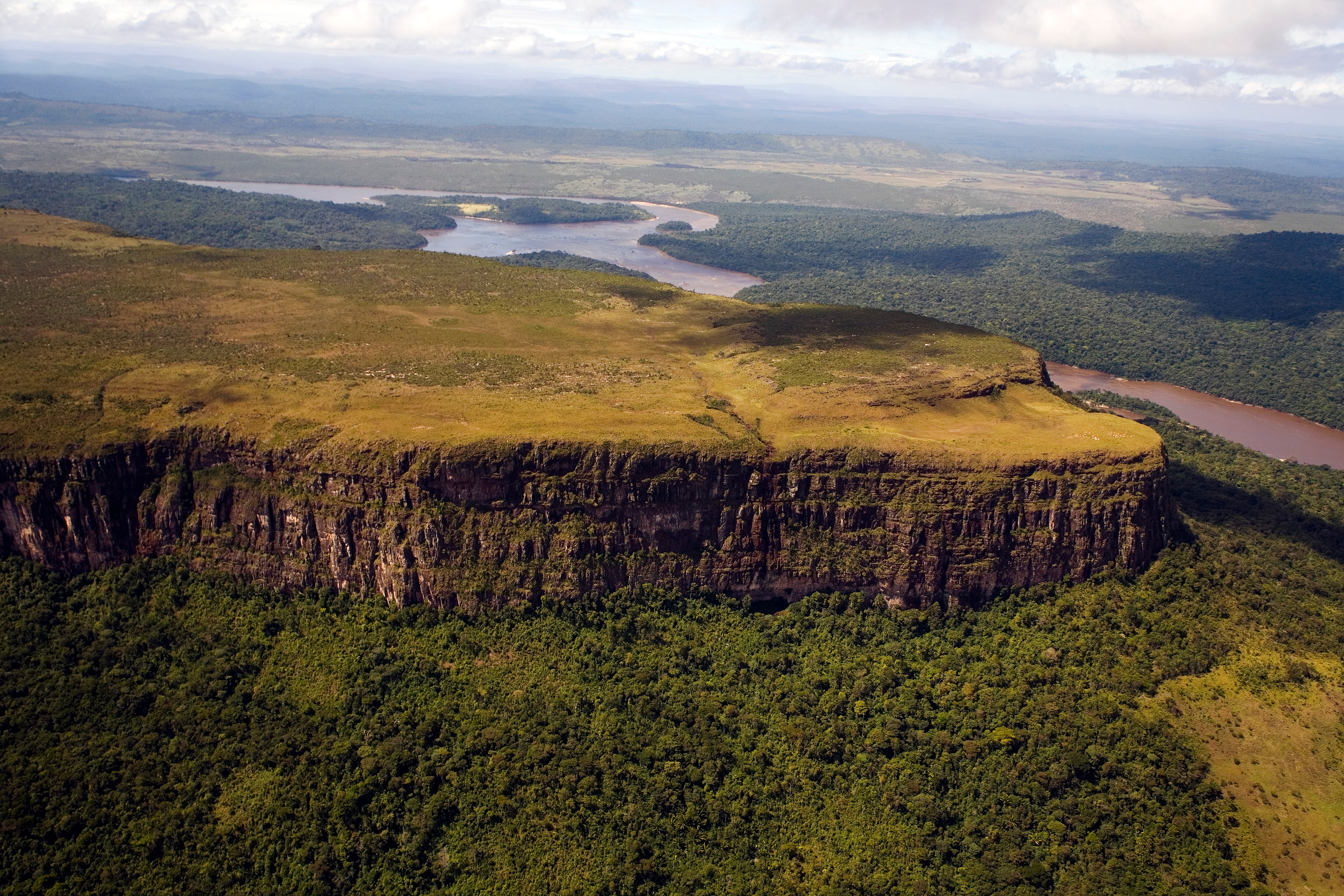 Venezuela, Bolivar State, Canaima National Park, Tepui mountain surrounded by a forest and a river shoot from above (Photo by: Eye Ubiquitous/Universal Images Group via Getty Images)