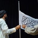 El portavoz talibán Zabihullah Mujahid poniendo una bandera del emirato talibán. (Photo by Hoshang Hashimi / AFP)