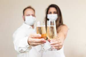Pareja con tapabocas protectoras celebrando con un vaso para beber. Pareja con tapabocas brindando.