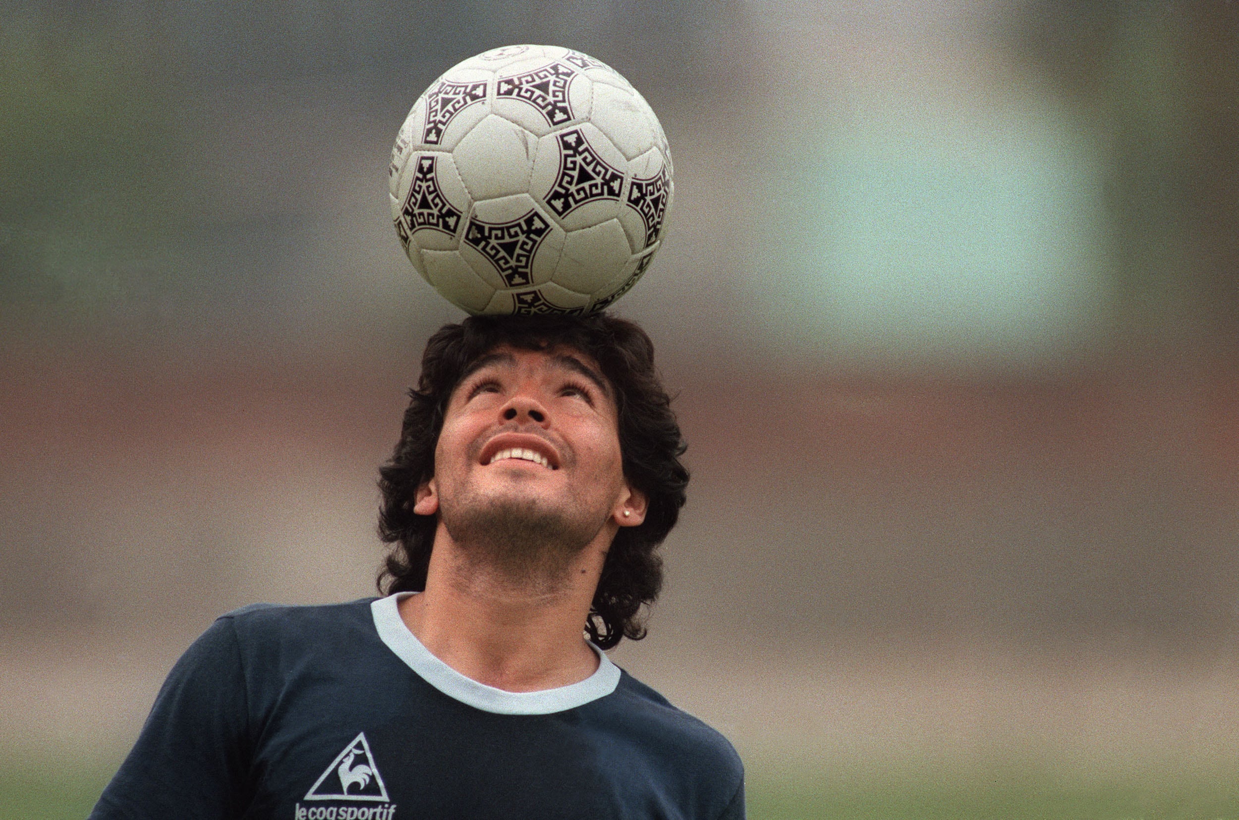 (ARCHIVO) El astro argentino del fútbol Diego Maradona, con un arete de diamantes, balancea un balón sobre la cabeza mientras abandona el campo de entrenamiento tras el entrenamiento de la selección nacional el 22 de mayo de 1986 en Ciudad de México. (Foto de JORGE DURAN / AFP)