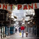 Una mujer pasea a su perro debajo de un letrero de "no entre en pánico" colgado en la entrada de un mercado de alimentos que fue cerrado para reducir la propagación del coronavirus, en Tel Aviv, Israel, el lunes 23 de marzo de 2020. En La vida diaria de Israel se ha cerrado en gran medida y los casos de COVID-19 se han multiplicado enormemente durante la última semana. Foto: AP / Oded Balilty.