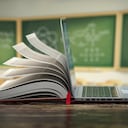 Educación en línea de aprendizaje electrónico o concepto de enciclopedia de Internet. Abra la computadora portátil y la compilación de libros en un salón de clases.