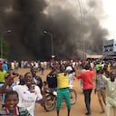 With the headquarters of the ruling party burning in the back, supporters of mutinous soldiers demonstrate in Niamey, Niger, Thursday, July 27 2023. Governing bodies in Africa condemned what they characterized as a coup attempt Wednesday against Niger's President Mohamed Bazoum, after members of the presidential guard declared they had seized power in a coup over the West African country's deteriorating security situation. (AP Photo/Fatahoulaye Hassane Midou)