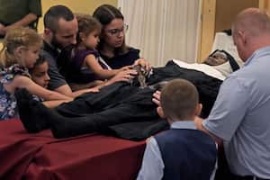 People pray over the body of Sister Wilhelmina Lancaster at the Benedictines of Mary, Queen of Apostles abbey Sunday, May 28, 2023, near Gower, Mo. Hundreds of people visited the small town in Missouri this week to see the nun's body that has barely decomposed since 2019 — some are saying it's a sign of holiness in Catholicism, while others are saying the lack of decomposition may not be as rare as people think. (AP Photo/Charlie Riedel)