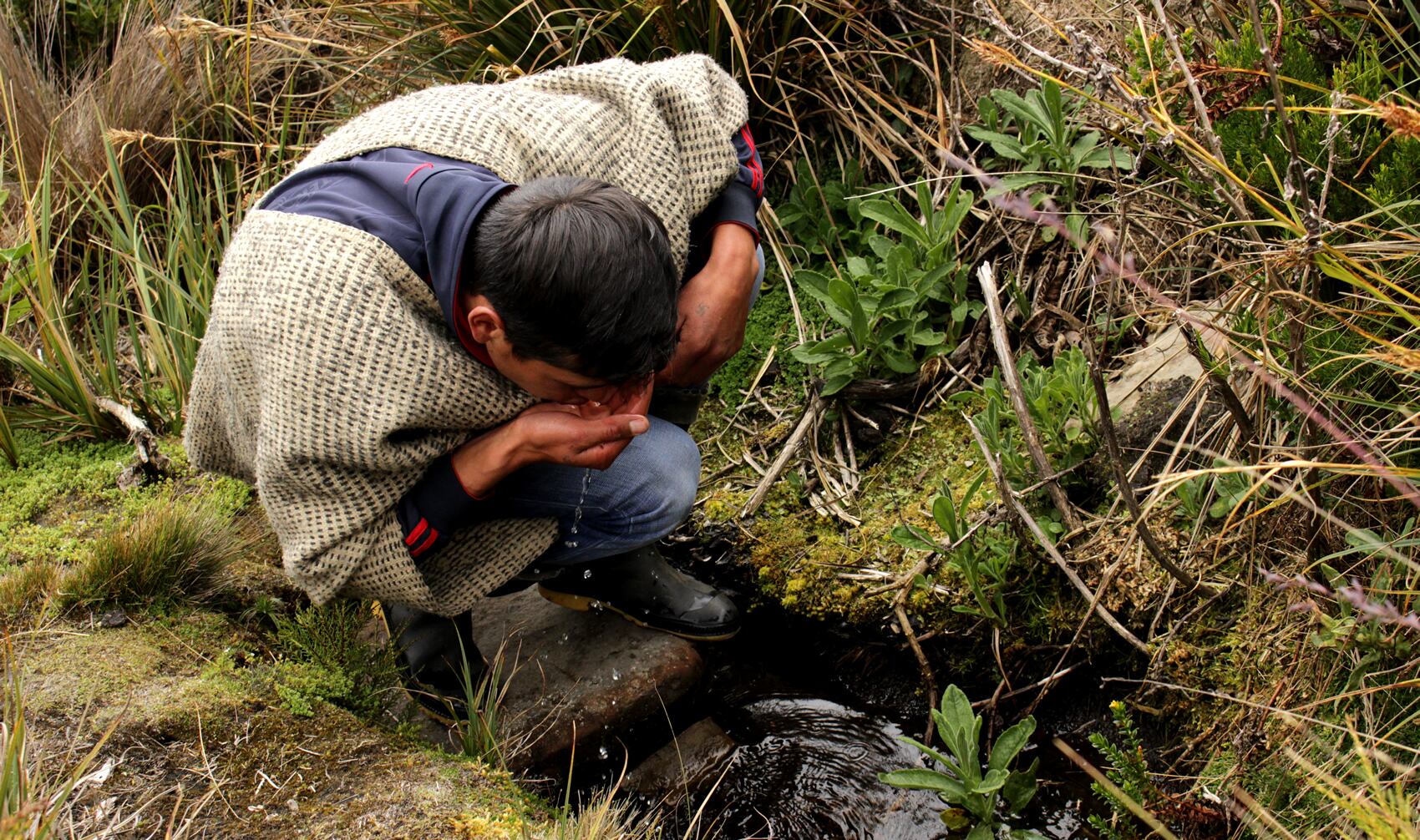 Un joven campesino bebe agua de un riachuelo de Sumapaz, el páramo más grande del mundo.