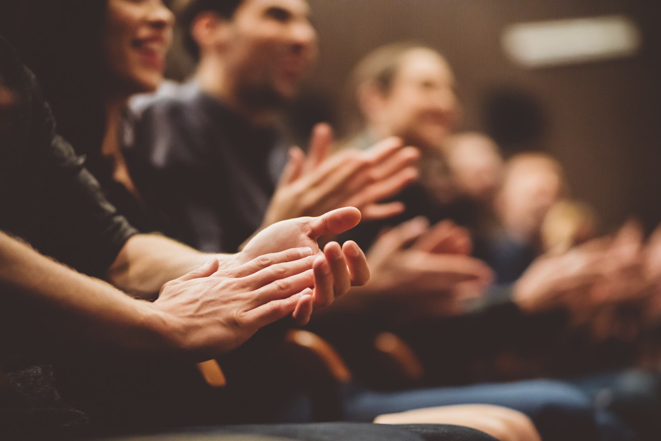 Group of people clapping hands in the theater, close up of hands. Dark tone.