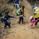 Una mujer trata de levantar a una niña de un paso enlodado mientras migrantes ecuatorianos atraviesan la selva del Darién para llegar desde Colombia a Panamá en su ruta hacia Estados Unidos, el 15 de octubre de 2022. (AP Foto/Fernando Vergara, Archivo)