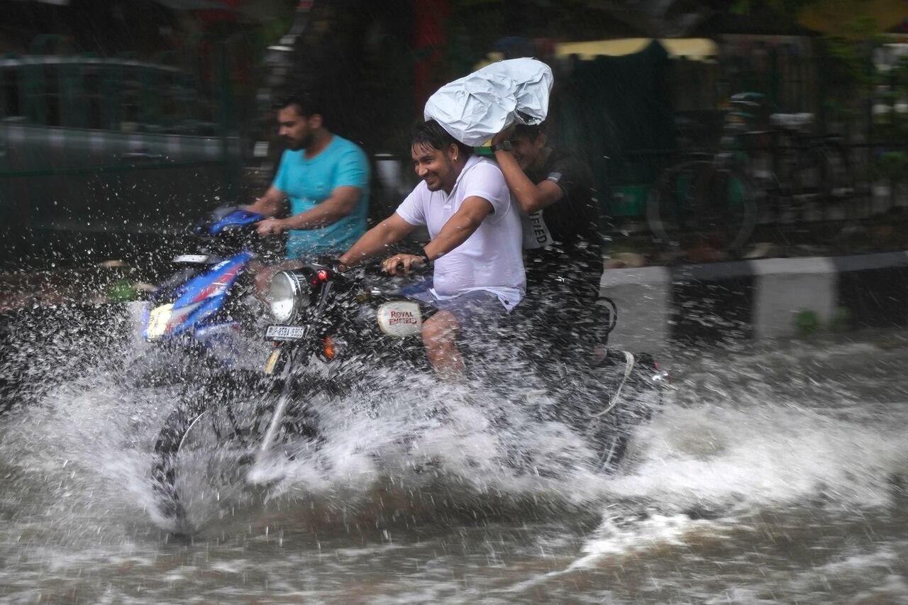 Un motociclista conduce por una calle anegada durante un fuerte aguacero en Nueva Delhi, India, el domingo 9 de julio de 2023.
