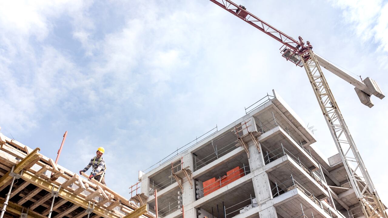 Vista del sitio de construcción con grúa torre, edificio en construcción, constructores