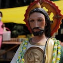 A woman walking behind the figure of San Judas Tadeo outside the Iglesia de San Hipolito in Mexico City, Mexico on May 28, 2020 during a Covid-19 health emergency. (Photo by Gerardo Vieyra/NurPhoto via Getty Images)