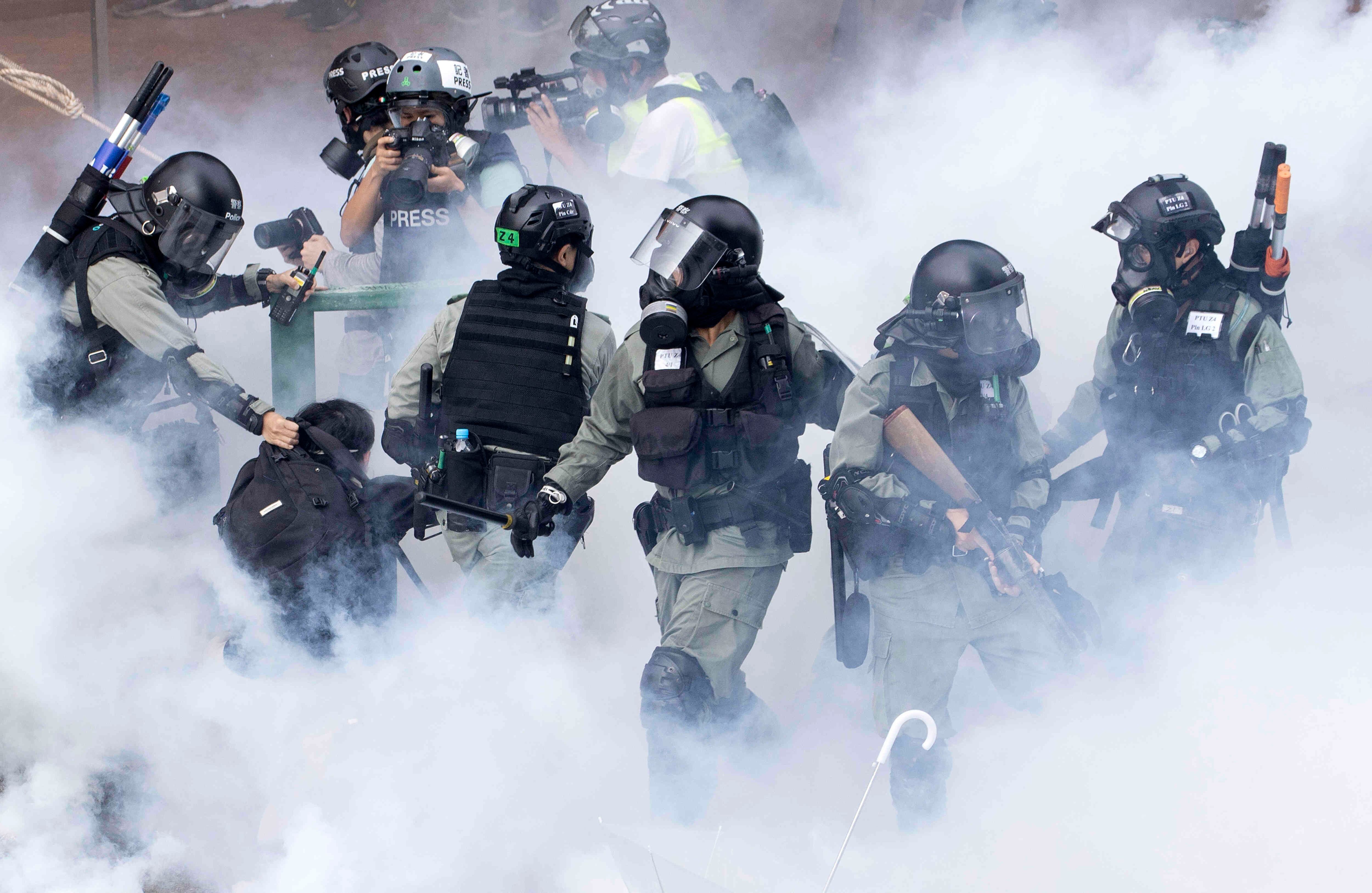 Entre una nube de gas lacrimógeno varios policías inician con los arrestos y detenciones a los manifestantes. Foto: AP/Ng Han Guan.