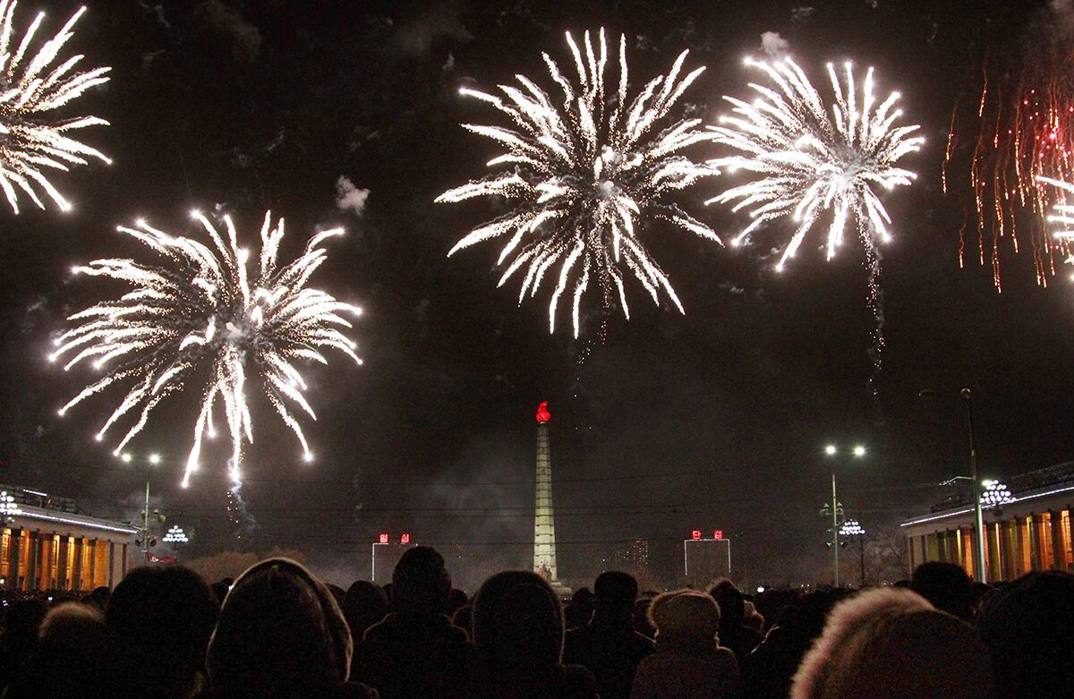 Los norcoreanos ven los fuegos artificiales explotar sobre la Torre de Juche. (AP)
