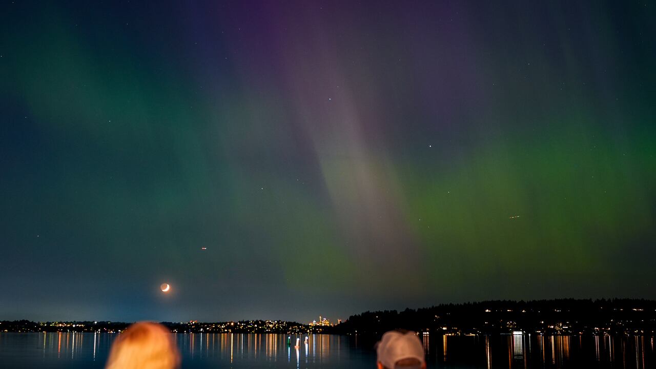 Un grupo de personas admira la aurora boreal que ilumina el lago Washington, en Renton.