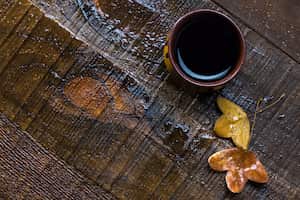 Taza de café negro y hojas de otoño sobre una vieja mesa de madera húmeda. plano