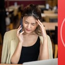 Mujer se agarra la cabeza mientras habla por celular.
