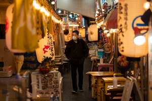 Un hombre con tapabocas camina por un pasillo lleno de restaurantes construidos debajo de las vías del tren en Tokio. Foto: AP / Hiro Komae.