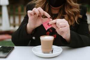 A young woman having a coffee wearing a protective face mask