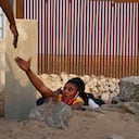 Un miembro de la familia migrante haitiana busca ayuda mientras emerge de un canal rocoso adyacente a una brecha en el muro fronterizo de los Estados Unidos en Yuma, Arizona, el miércoles 9 de junio de 2021. Foto: AP / Eugene García.