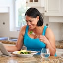 Mujer con sobrepeso con tableta digital que controla la ingesta de calorías con tableta digital