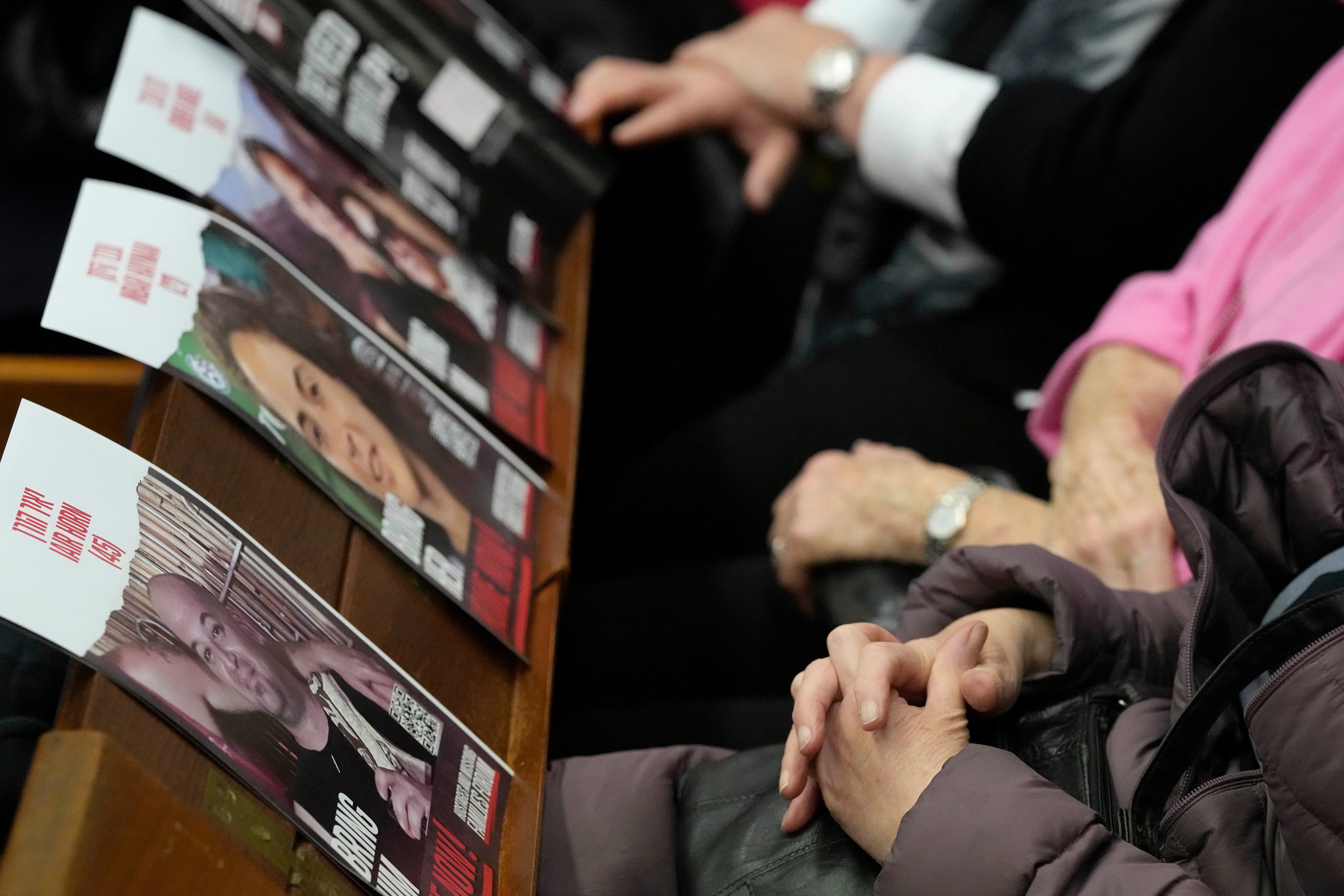 Miembros de la comunidad judía se sientan detrás de carteles que muestran rehenes mientras se reúnen para conmemorarlos después de que fueron capturados en los ataques de Hamas del 7 de octubre