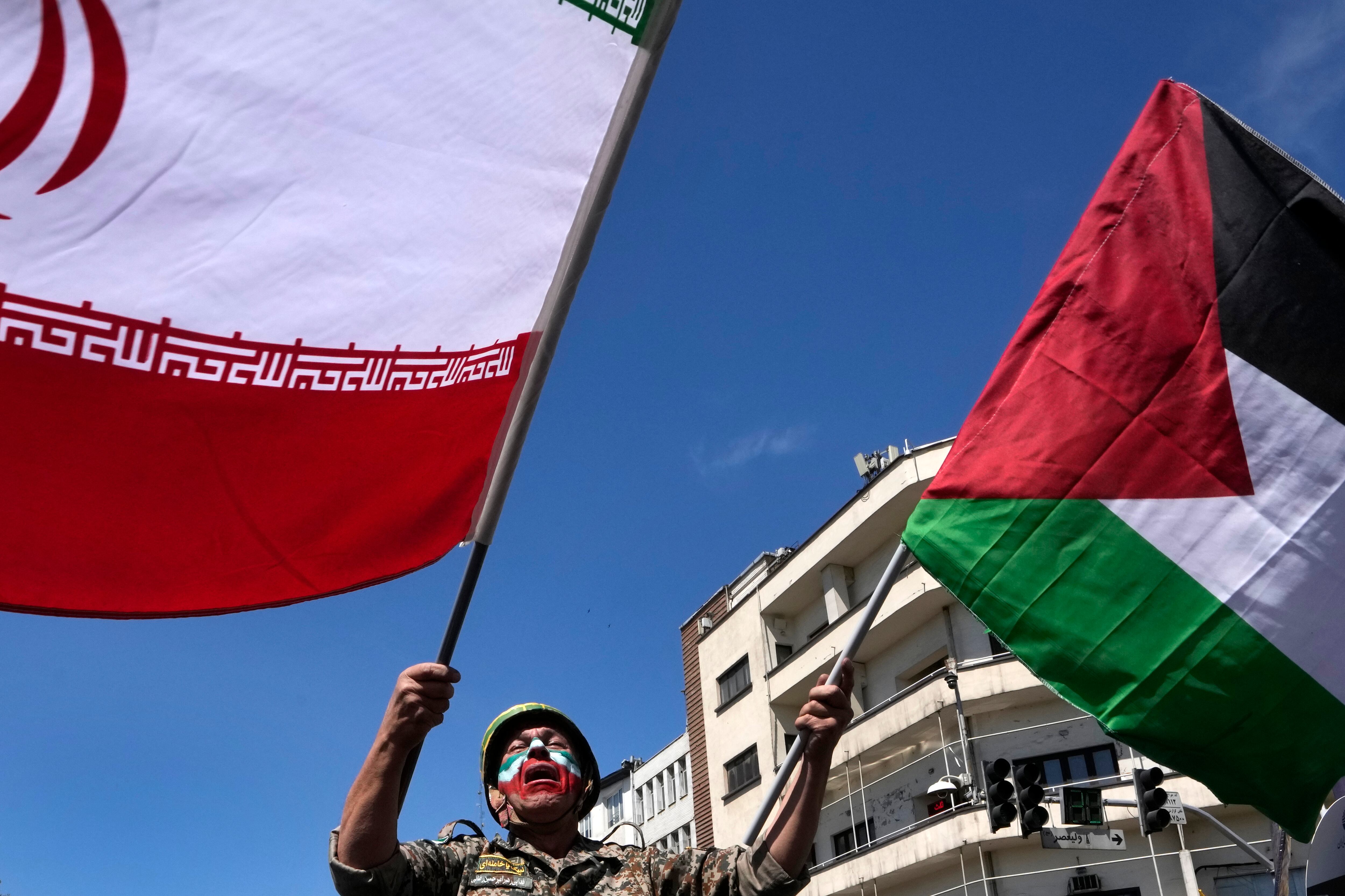 With his face painted in the colors of the Iranian flag, a man weeps as he waves Iranian and Palestinian flags in the annual rally to mark Quds Day, or Jerusalem Day, in support of Palestinians, in Tehran, Iran, Friday, April 5, 2024. In the rally in Tehran, thousands attended a funeral procession for the seven Revolutionary Guard members killed in an airstrike widely attributed to Israel that destroyed Iran's Consulate in the Syrian capital on Monday. (AP Photo/Vahid Salemi)