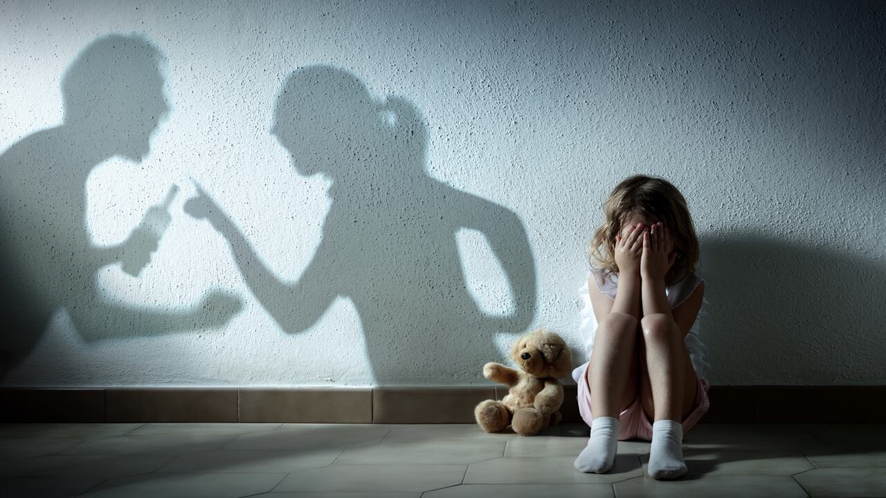 Niña llorando con sombra de padres discutiendo - Violencia doméstica y divorcio