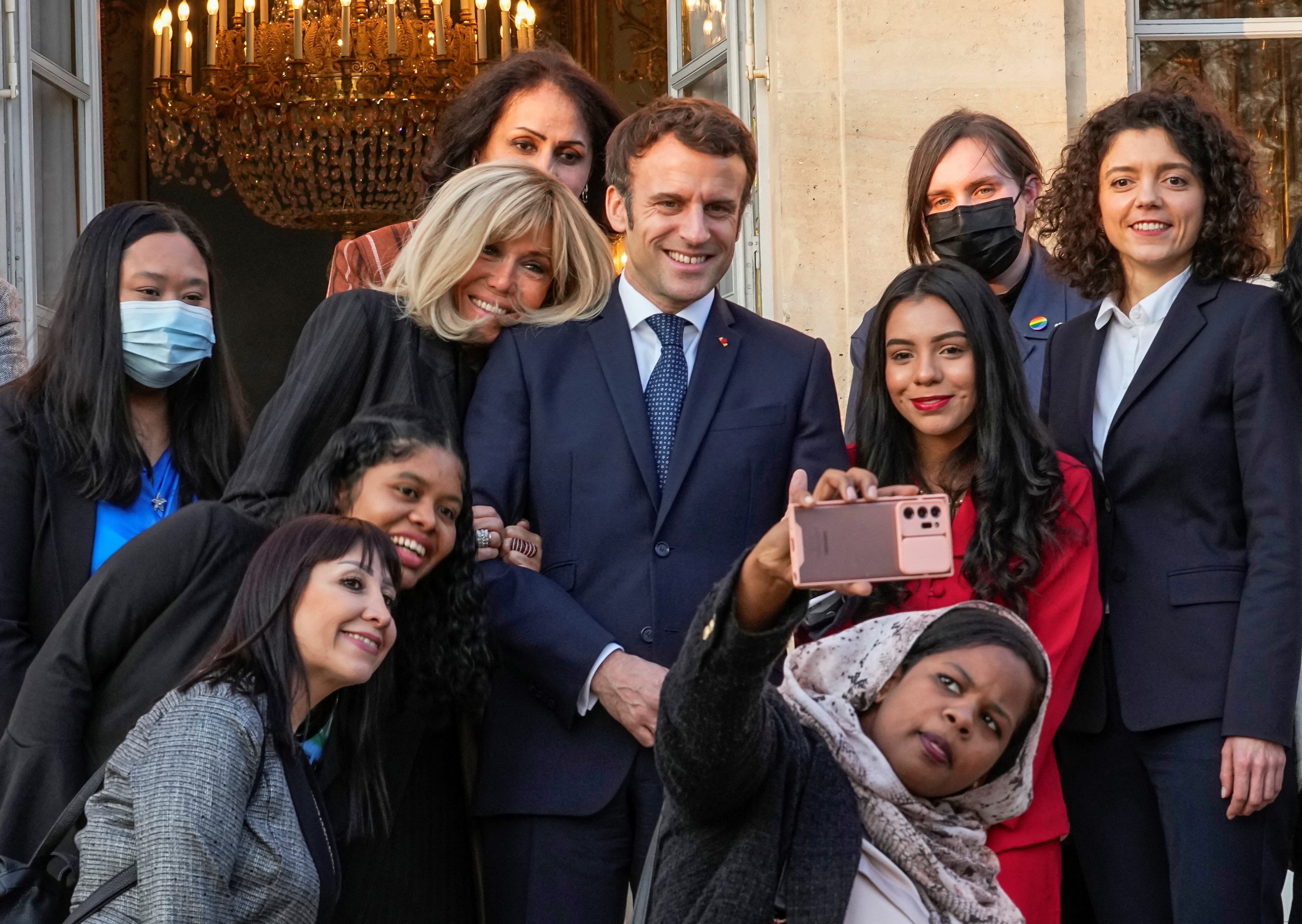 El presidente francés Emmanuel Macron (C) y su esposa Brigitte Macron posan para una foto grupal con los primeros galardonados de la Iniciativa Marianne para los Defensores de los Derechos Humanos luego de una ceremonia de premiación como parte del Día Internacional de la Mujer, en el palacio del Elíseo en París, en marzo. 8 de enero de 2022. (Foto de Michel EULER / POOL / AFP)
