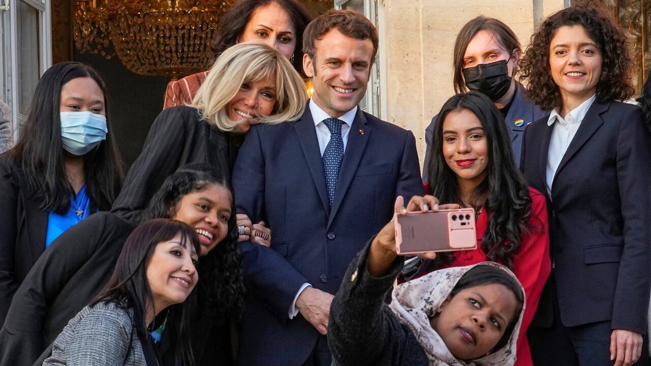El presidente francés Emmanuel Macron (C) y su esposa Brigitte Macron posan para una foto grupal con los primeros galardonados de la Iniciativa Marianne para los Defensores de los Derechos Humanos luego de una ceremonia de premiación como parte del Día Internacional de la Mujer, en el palacio del Elíseo en París, en marzo. Foto: Michel Euler/Pool/AFP.
