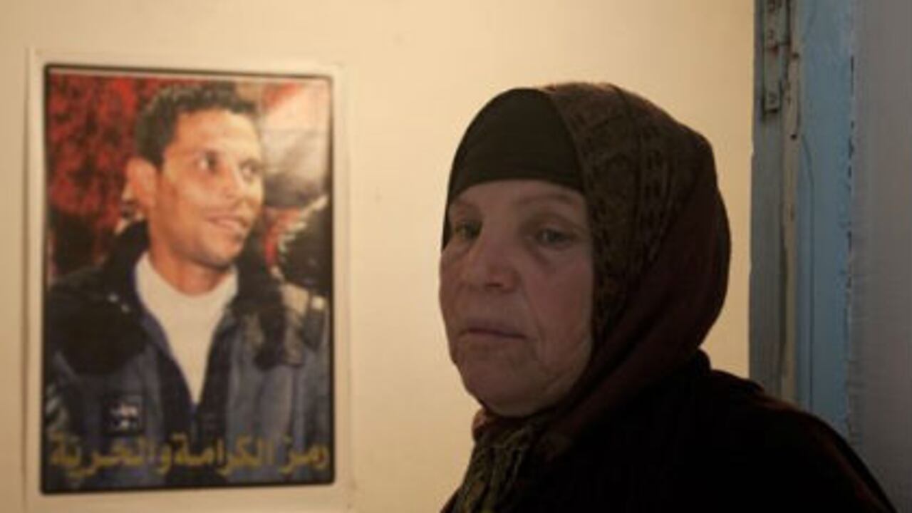 Manoubiyeh Bouazizi, la madre de Mohamed Bouazizi, posa en una foto junto al cartel de su hijo, que se inmoló hace un año.