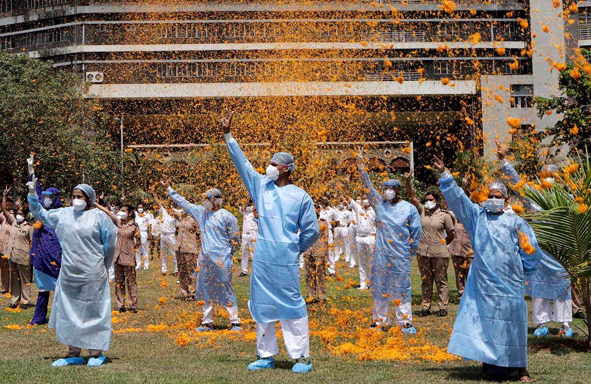 Un helicóptero de la Fuerza Aérea India esparce pétalos de flores sobre el personal del hospital INS Asvini en Mumbai, el domingo 3 de mayo. El evento fue parte de los esfuerzos que las Fuerzas Armadas hacen para agradecer a los trabajadores, incluidos médicos, enfermeras y personal de policía, que han estado a la vanguardia de la batalla del país contra la pandemia de coronavirus. Foto: Rajanish Kakade / AP.