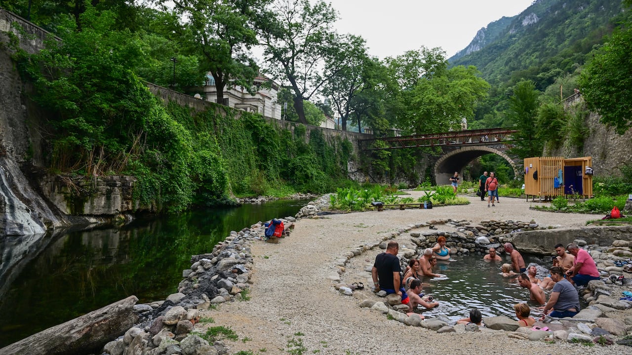 Los turistas disfrutan de aguas termales sulfurosas en piscinas ajardinadas restauradas por un grupo de jóvenes arquitectos liderados por Oana Chirila, junto al lecho del río Cerna en Baile Herculane el 29 de julio de 2025.
