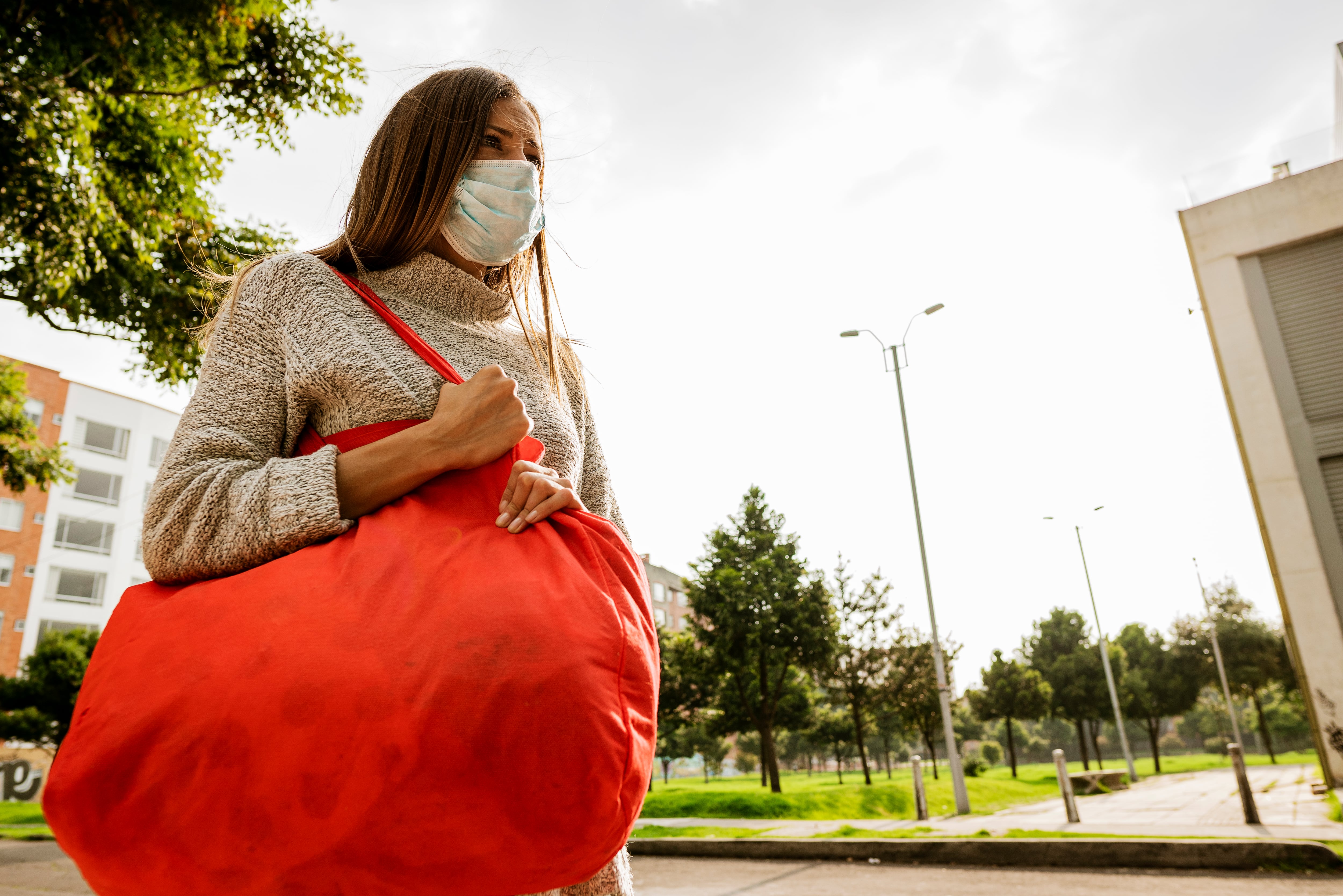 Hermosa mujer latina de Bogotá Colombia de entre 20 y 29 años sale con su bolsa de compras por comida a la calle en tiempos de cuarentena, con mucho miedo porque la ciudad está sola
