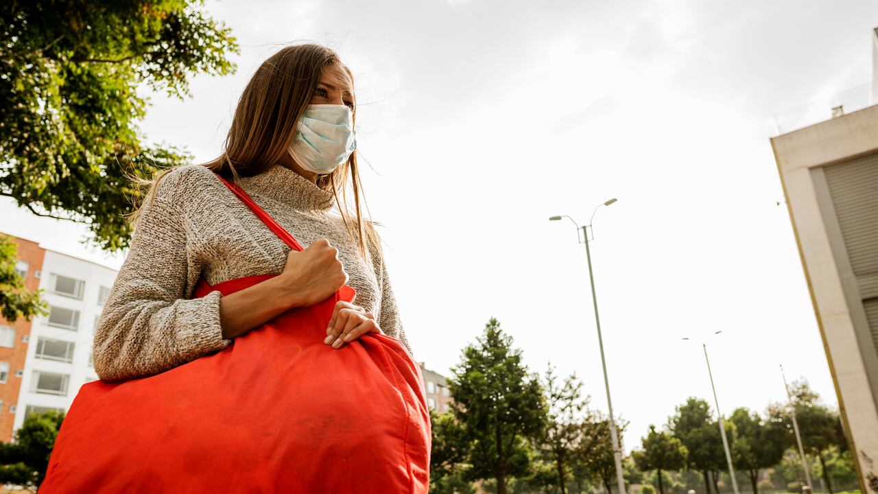 Hermosa mujer latina de Bogotá Colombia de entre 20 y 29 años sale con su bolsa de compras por comida a la calle en tiempos de cuarentena, con mucho miedo porque la ciudad está sola