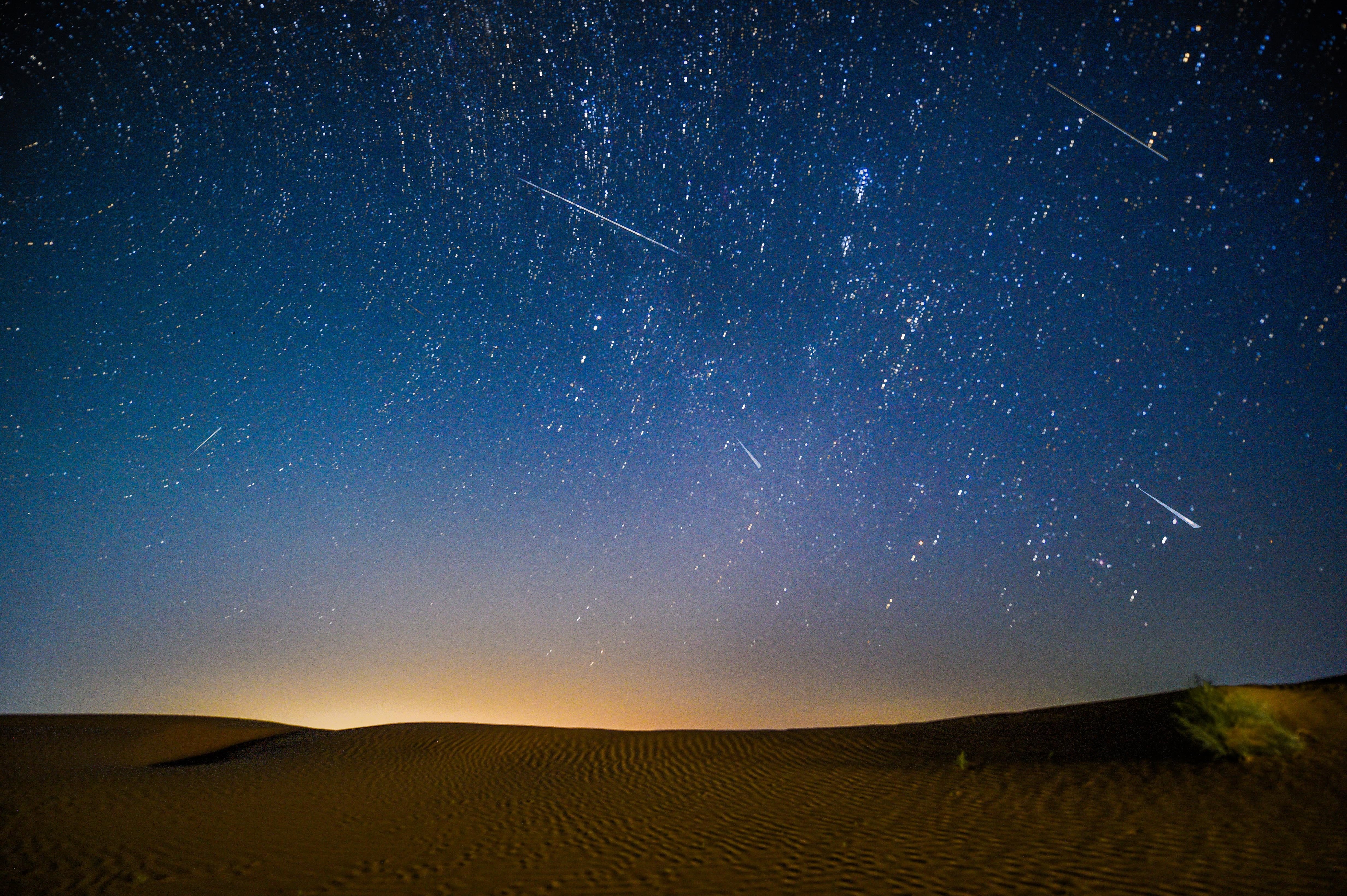 Fotomontaje tomado el 13 de agosto de 2021 que muestra el cielo nocturno durante la lluvia de meteoritos de las Perseidas sobre una zona de demostración ecológica de Engebei en el desierto de Kubuqi